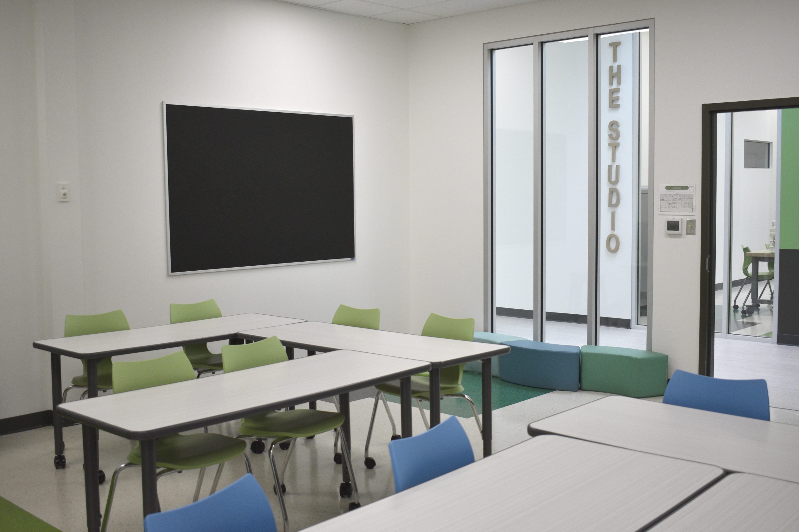 A modern classroom featuring a table with green chairs