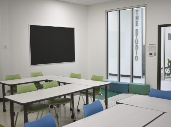 A modern classroom featuring a table with green chairs