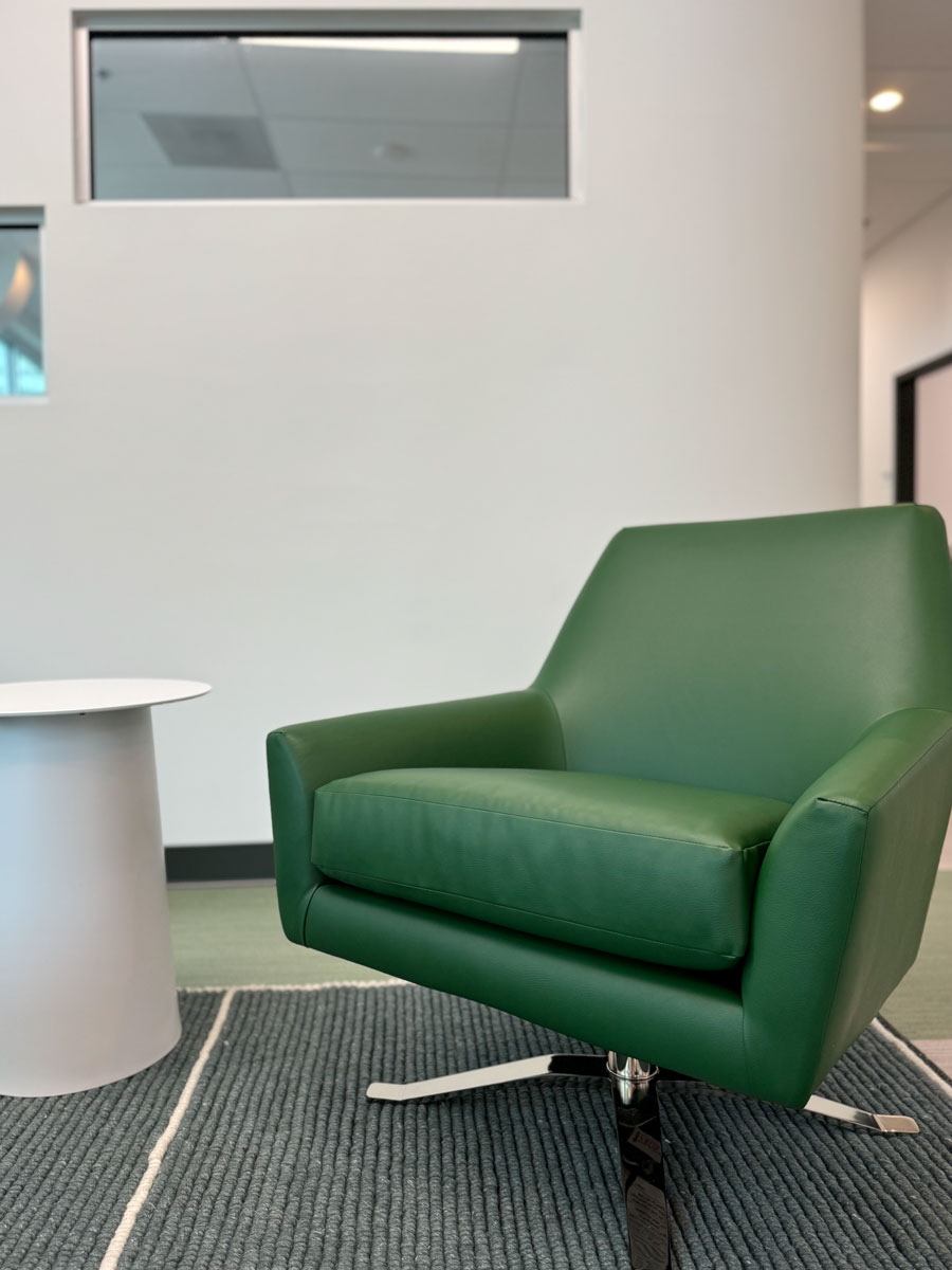 green leather swivel chair paired with a white side table, set on a textured rug in a well-lit space.
