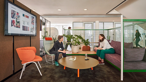 workers meet in a well-lit and colorful private community based space with integrated technology